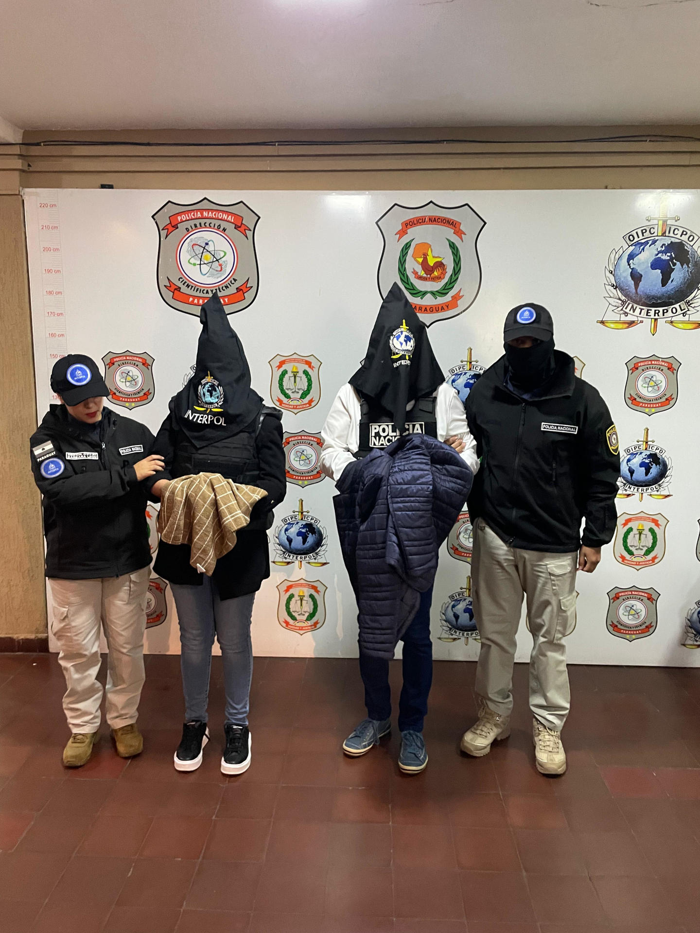 Fotografía cedida del exsenador argentino Edgardo Kueider (c-d) y la secretaria del exsenador, Iara Guinsel (c-i), durante su detención este 29 de julio de 2025, en Asunción (Paraguay). EFE/ Interpol Paraguay