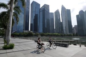 Fotografía de archivo, tomada el 28/04/2021, que muestra a dos mujeres en bicicletas en el distrito financiero de Singapur. EFE/EPA/WALLACE WOON