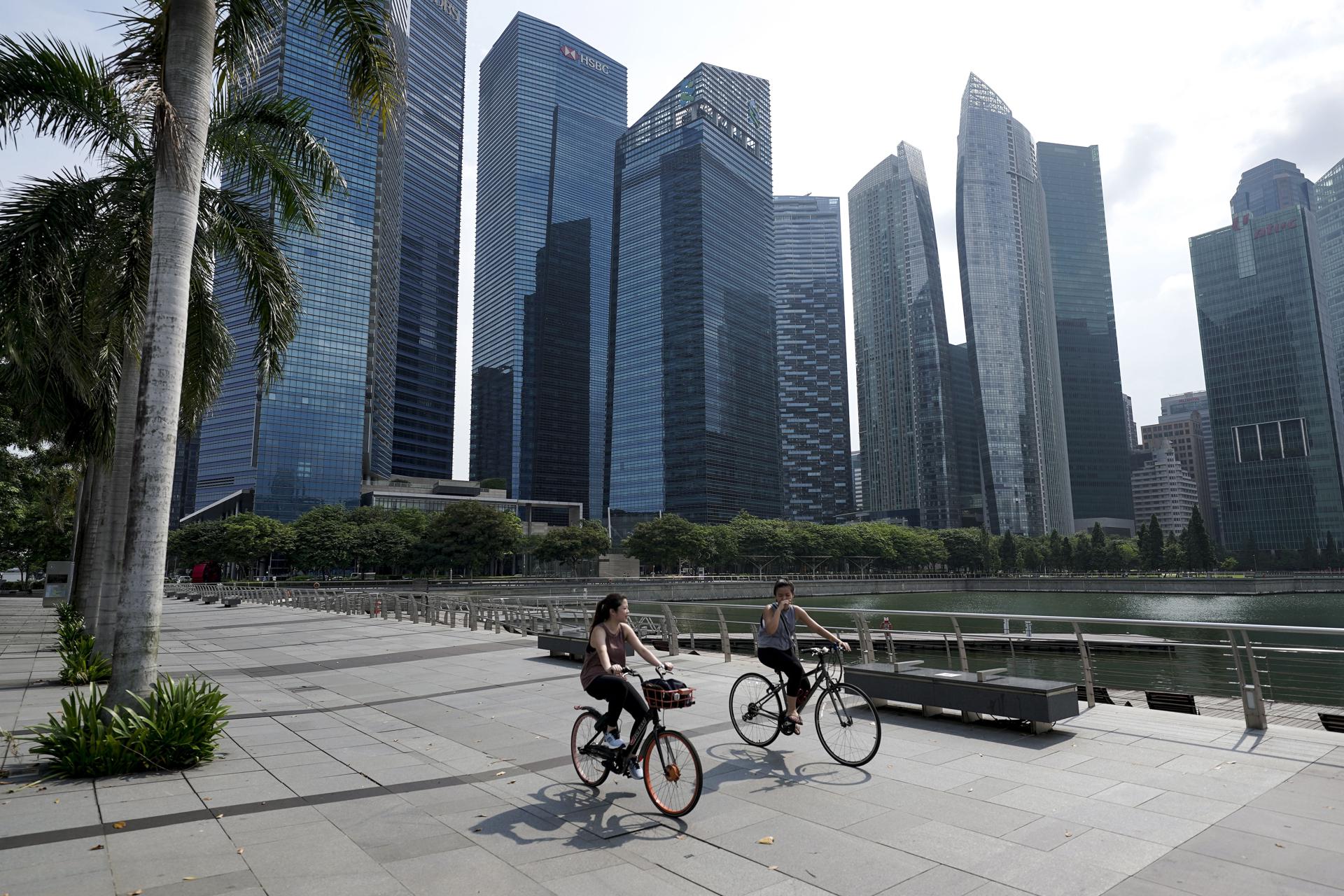 Fotografía de archivo, tomada el 28/04/2021, que muestra a dos mujeres en bicicletas en el distrito financiero de Singapur. EFE/EPA/WALLACE WOON