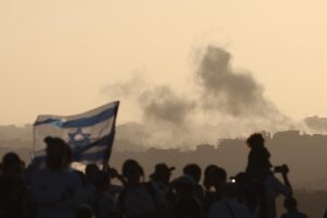 El humo se eleva desde Gaza después de un ataque aéreo israelí, mientras colonos israelíes radicales se manifiestan pidiendo el regreso de los asentamientos judíos en Gaza, en una zona cercana a la frontera con la Franja de Gaza, este miércoles.- EFE/ Abir Sultan