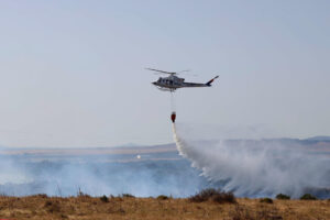 Un helicóptero intenta sofocar las llamas del incendio que se ha producido en el paraje de El Pedregoso, iniciado en un aerogenerador, en la localidad de Facinas (Tarifa). EFE/A.Carrasco Ragel.