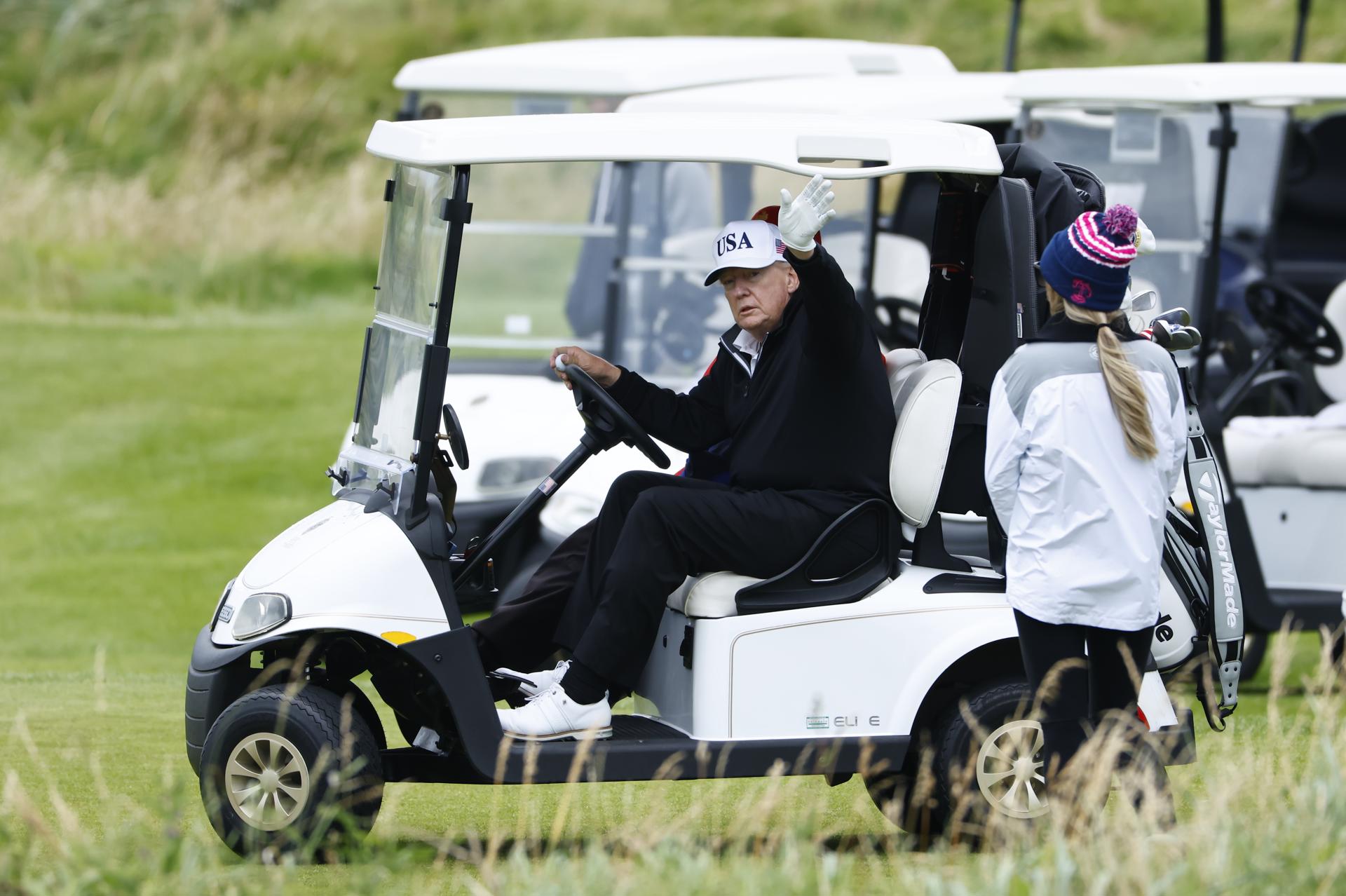 El presidente de EE.UU., Donald Trump, saluda desde su carrito de golf mientras juega en el campo de golf Trump Turnberry durante una visita privada en Turnberry, Escocia, Reino Unido, el 27 de julio de 2025. EFE/EPA/TOLGA AKMEN