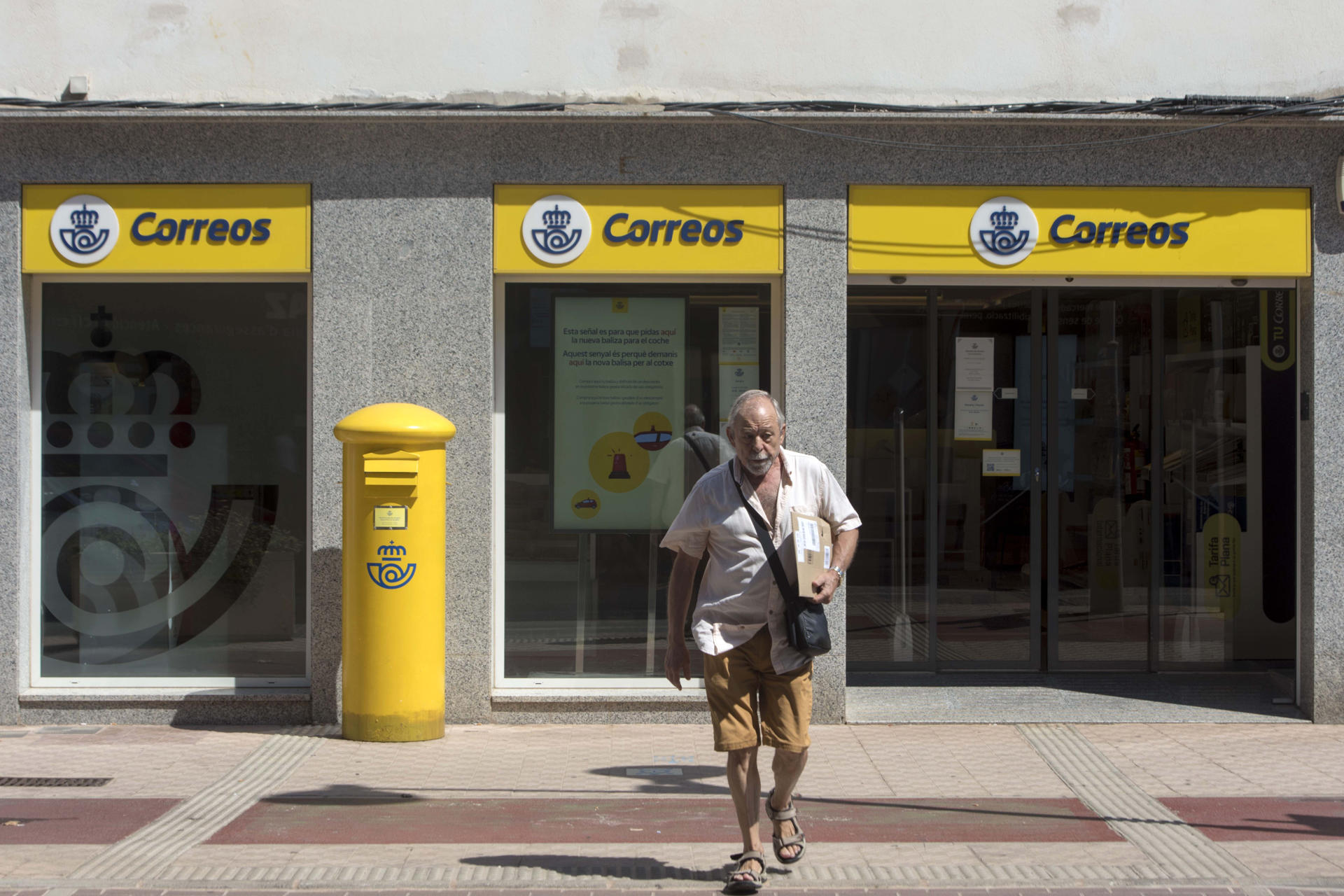 Imagen de archivo de un hombre que sale de la oficina principal de correos de Mahón. EFE/David Arquimbau Sintes