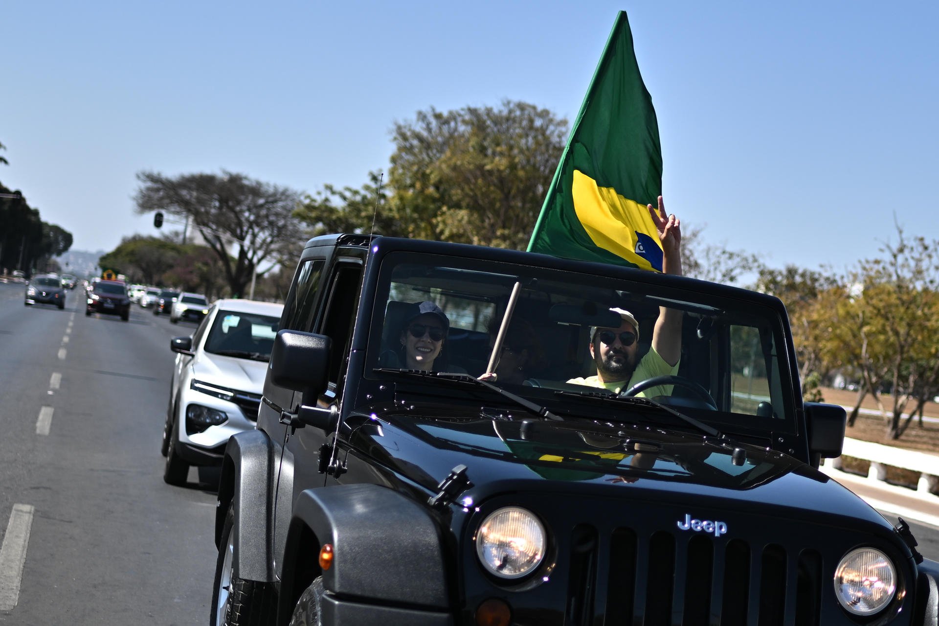 Simpatizantes del expresidente de Brasil, Jair Bolsonaro, sostienen una bandera durante una caravana este domingo, en la Explanada de los Ministerios en Brasilia (Brasil). EFE/ Andre Borges