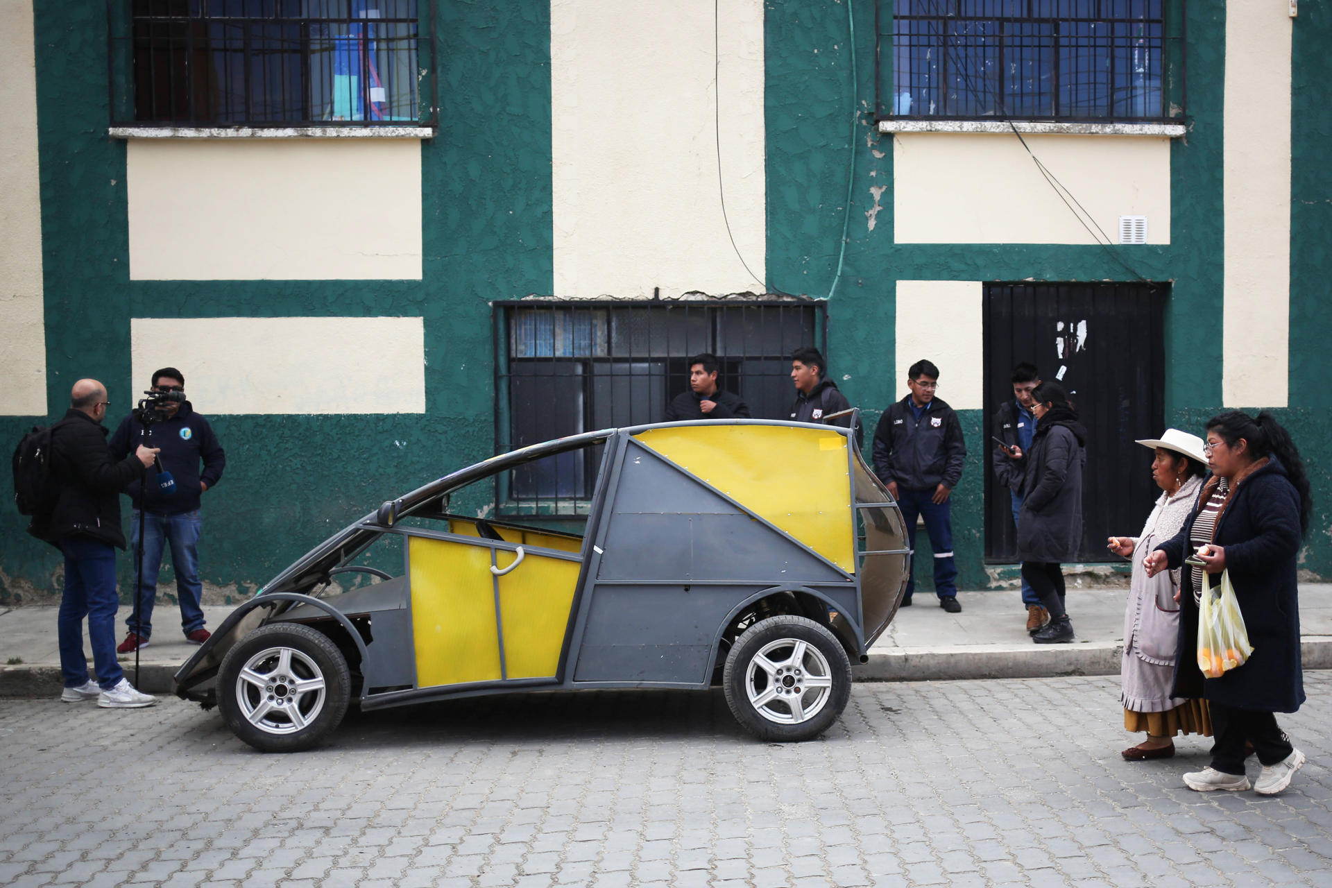 Fotografía del 3 de julio de 2025 de personas caminando junto al auto eléctrico 'Katari MRC5' en El Alto (Bolivia). EFE/ Luis Gandarillas