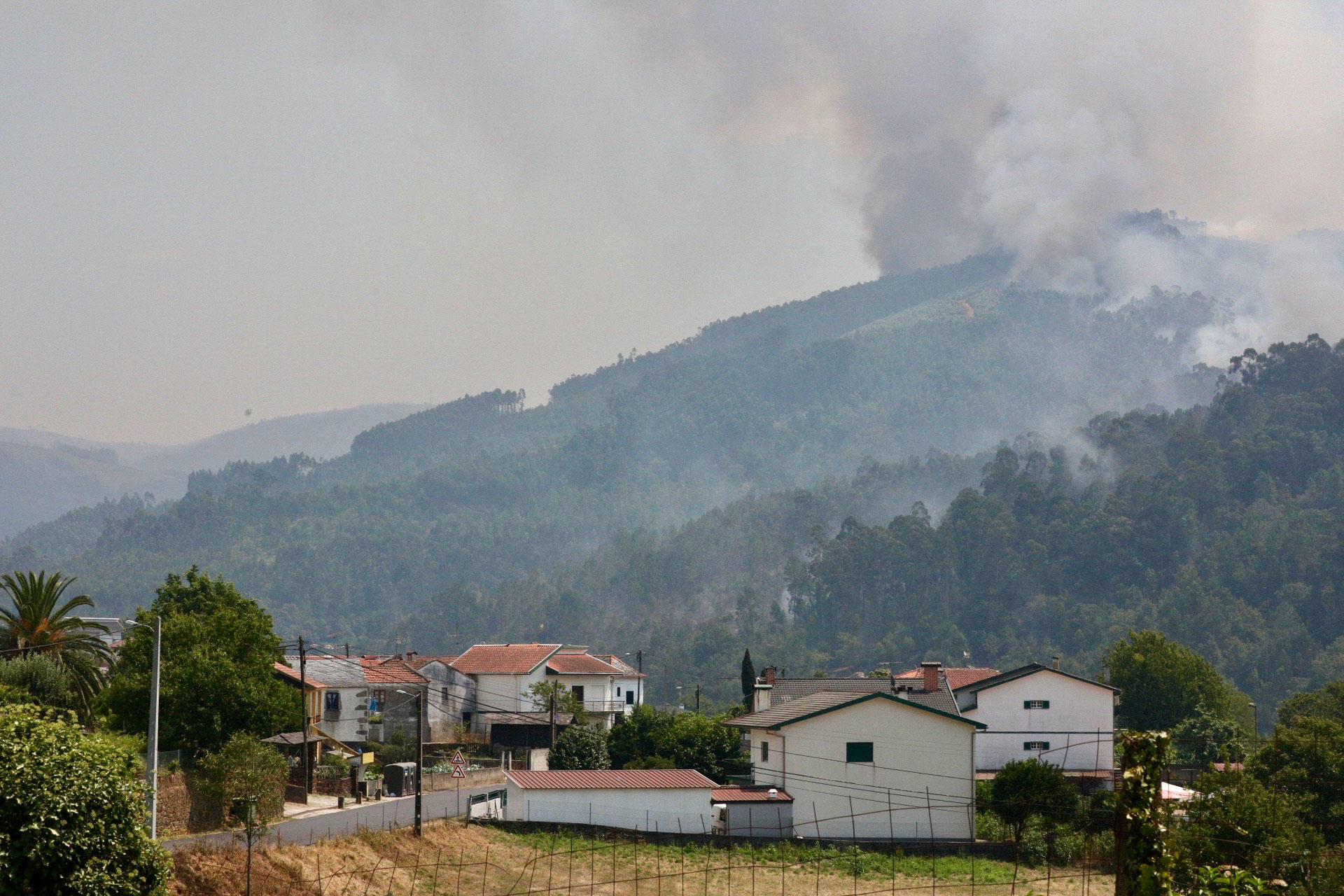 Tres mujeres bomberas descansan junto a una carretera, en un turno que llega a las 24 horas de guardia, mientras vigilan el Museo de Fósiles del Geoparque de Arouca, cuyos alrededores han sido pasto de las llamas. EFE/Carlos Garcia