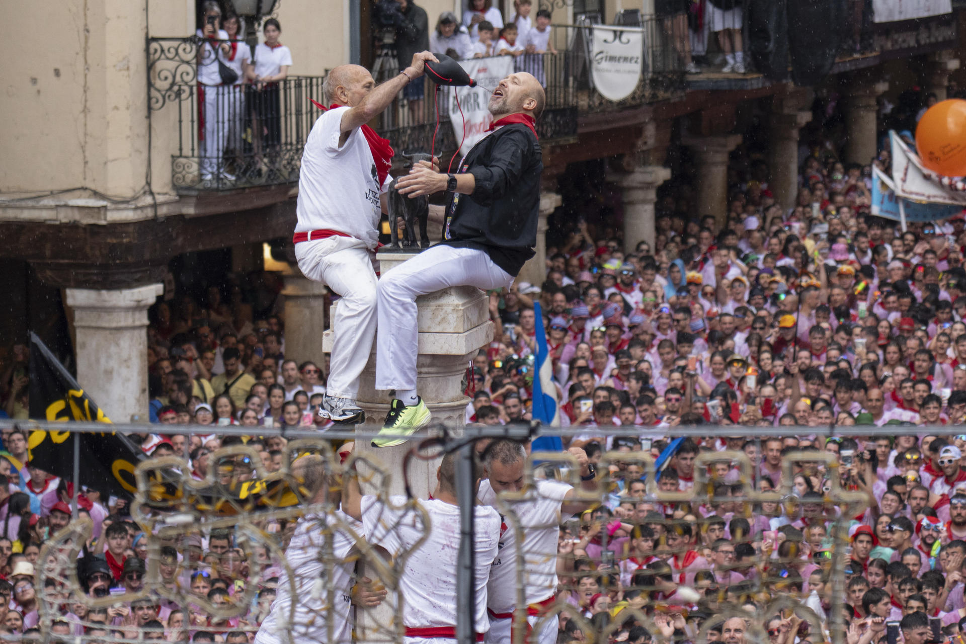 Segundo Pascual y Miguel Ángel Pérez, de la Peña El Despadre, son los encargados de colocar el característico pañuelo rojo al Torico de Teruel, tras trepar por la columna de la fuente del Torico ante la emoción y los vítores de miles de personas congregadas en la plaza del Torico. EFE/ Antonio Garcia
