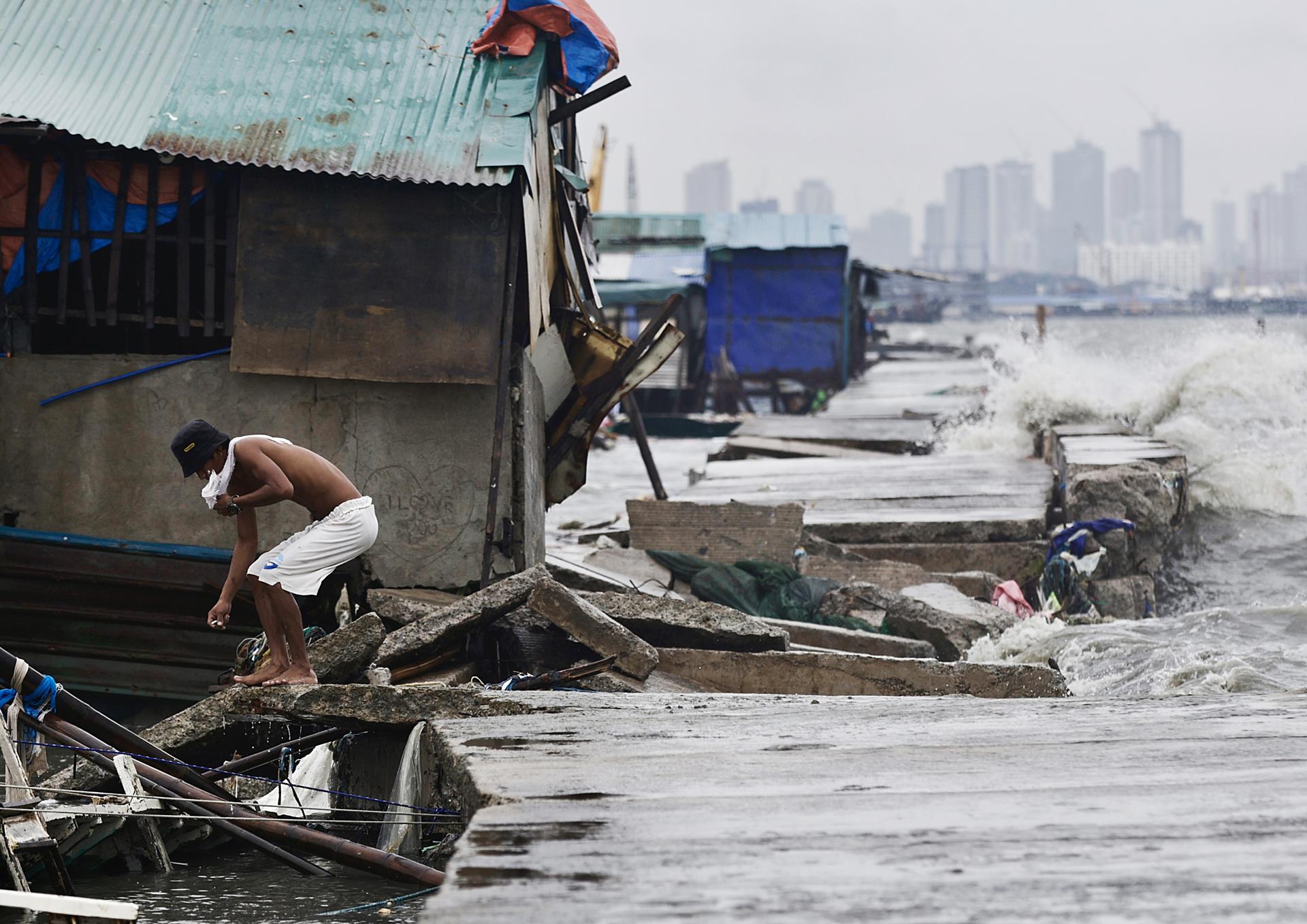 NAVOTAS CITY (Philippines), 25/07/2025.- A villager walks along a damaged dike brought by strong waves in Navotas city, Metro Manila, Philippines, 25 July 2025. The Philippine National Disaster Risk Reduction and Management Council (NDRRMC) reported on 25 July that the death toll from the combined effects of over a week of storms was recorded at 25 and more than a million families are affected as Tropical Storm Co-May battered the northern part of main Philippine island, Luzon. (tormenta, Filipinas) EFE/EPA/FRANCIS R. MALASIG