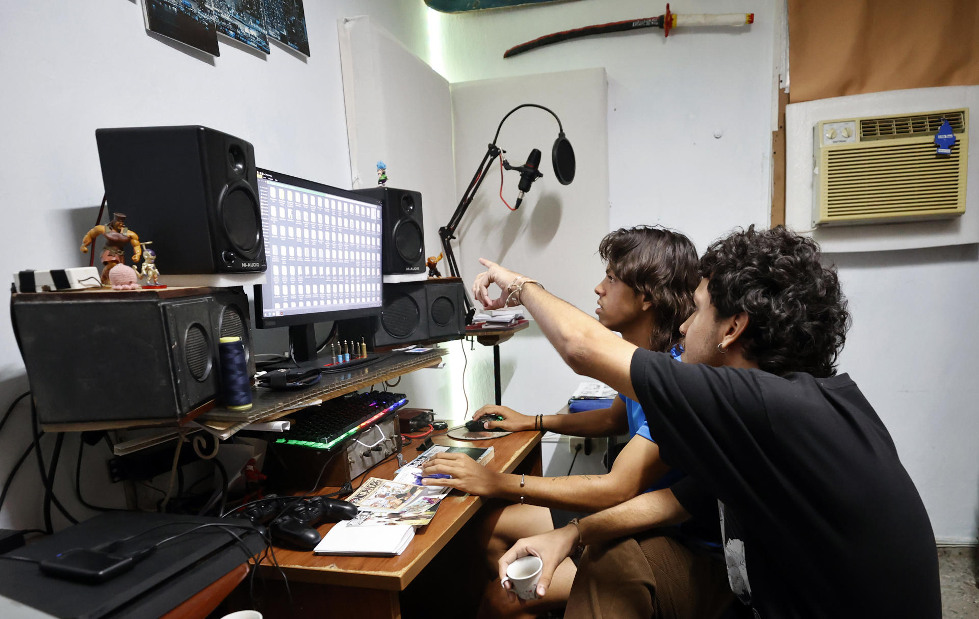 Alex Jiménez (i) y su amigo José Ángel González, trabajan en la edición de libros de Manga este miércoles, en La Habana (Cuba). El cuarto de Álex Jiménez, cubano de 21 años, es un centro de operaciones con una katana sobre la pared, un escritorio con muñecos de Dragon Ball Z y una almohadilla de ratón de Death Note. EFE/Ernesto Mastrascusa