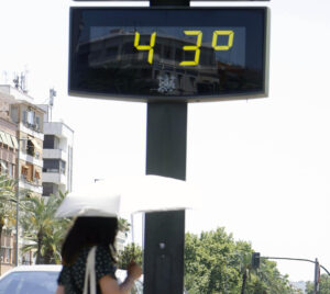 Imagen de archivo (27/06/2025) de una mujer cubierta con una sombrilla junto a un termómetro de calle que marca 43 grados.
EFE /Salas