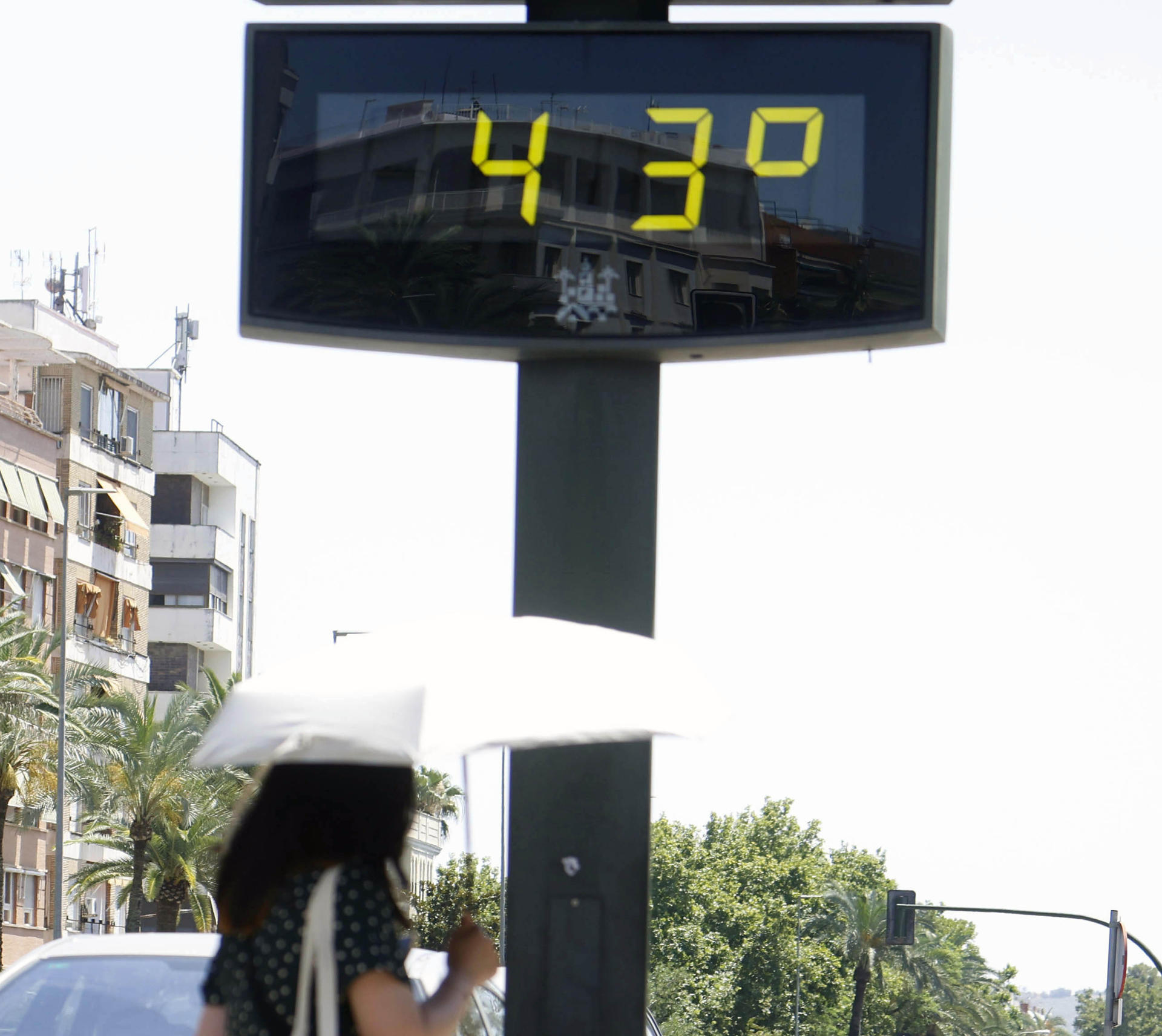 Imagen de archivo (27/06/2025) de una mujer cubierta con una sombrilla junto a un termómetro de calle que marca 43 grados.
EFE /Salas