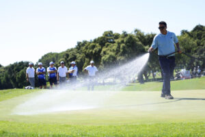 Un operario del campo riega el green del hoyo 11 momentos antes de suspender los últimos hoyos por el fuerte viento, en la primera jornada de la tercera edición del LIV Golf Andalucía 2025, el circuito de golf financiado por Arabia Saudí, este viernes en el campo de Valderrama en San Roque (Cádiz). EFE/A.Carrasco Ragel.
