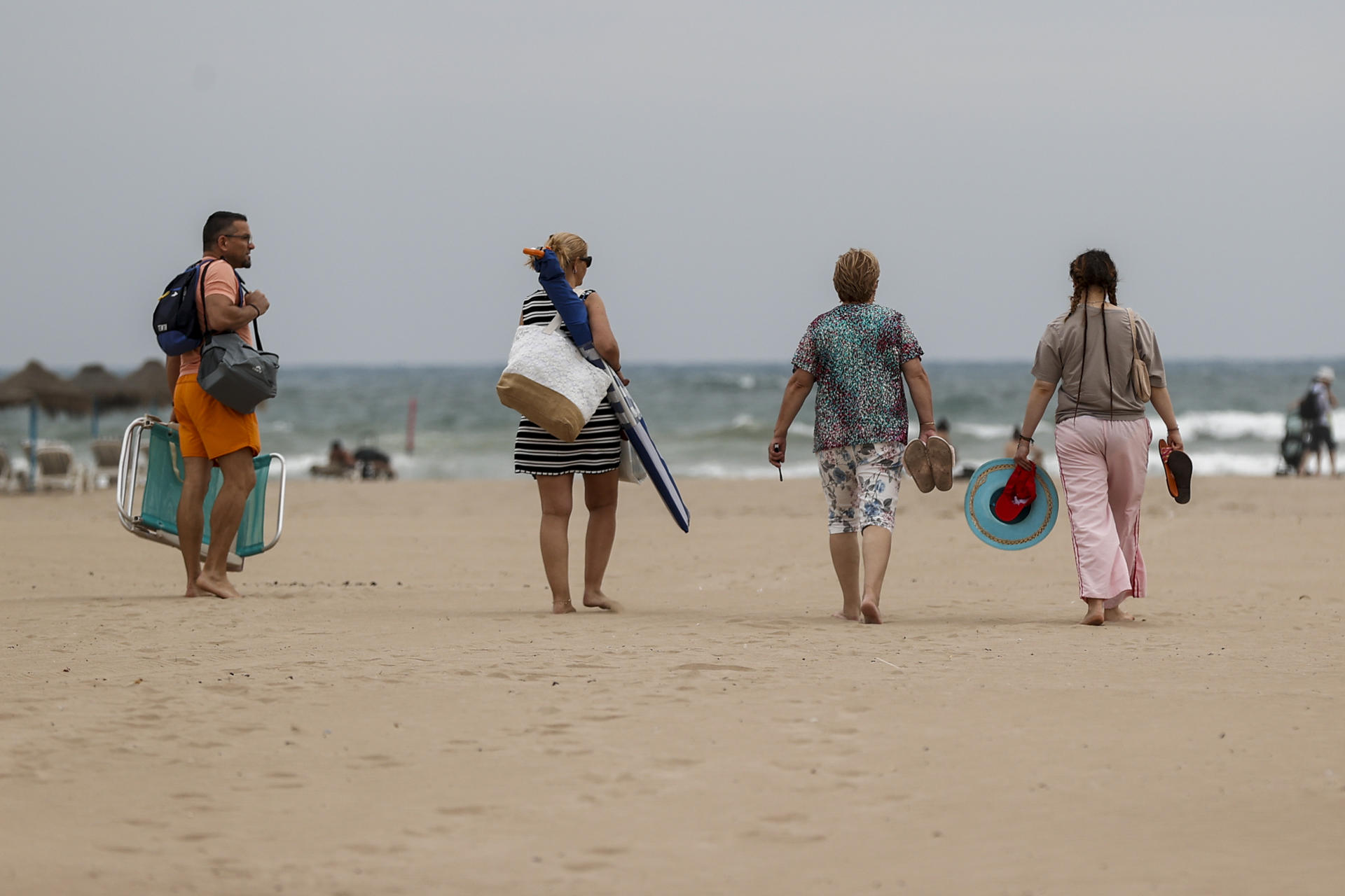 Varias personas se dirigen la playa de la Malvarrosa durante este martes. EFE/Manuel Bruque
