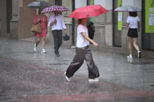 Varias personas caminan este miércoles por una calle de la ciudad de Castellón bajo una intensa lluvia. EFE/Andreu Esteban