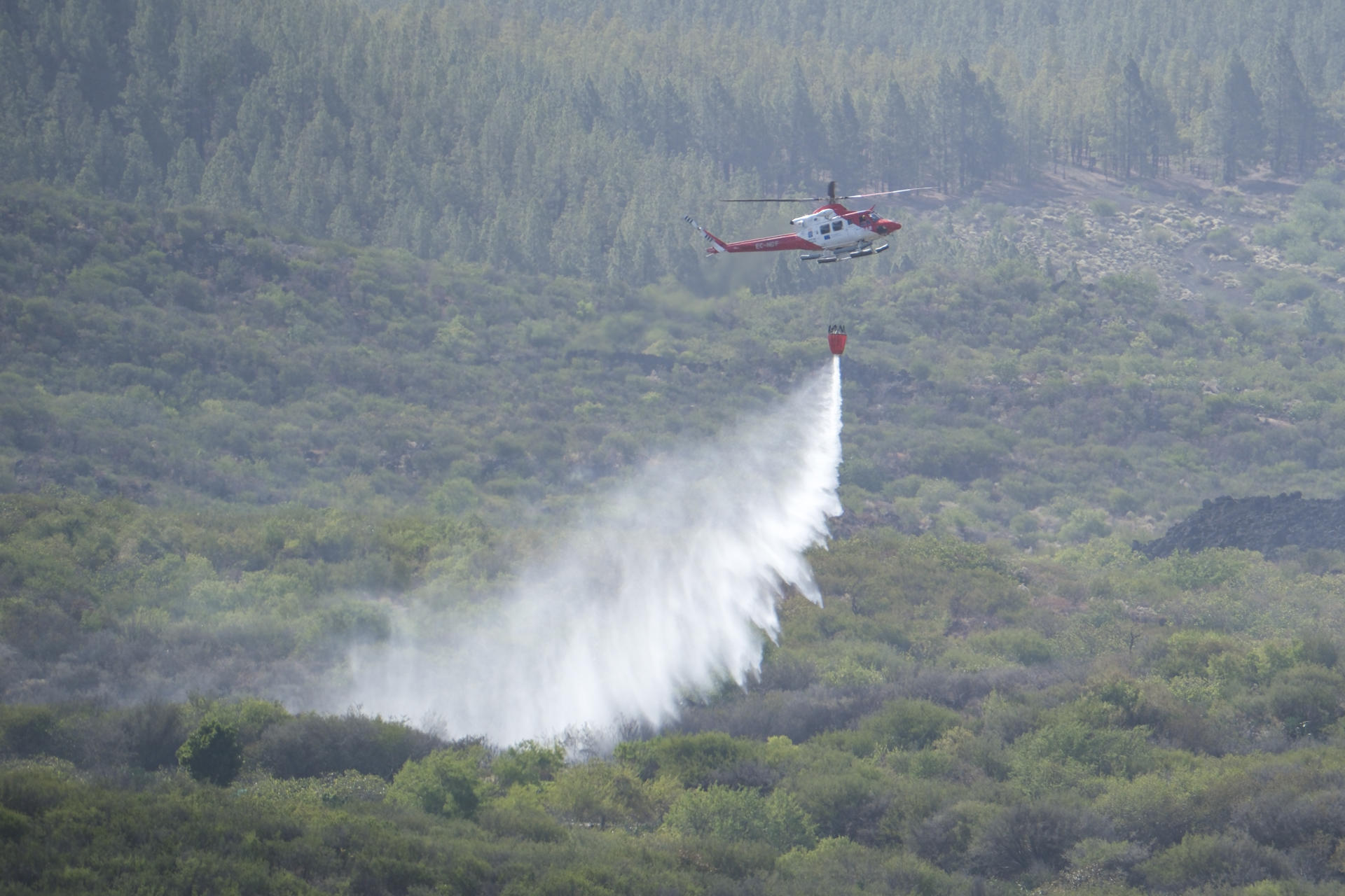 En la imagen, un helicóptero del Gobierno de Canarias descarga agua sobre la zona afectada, en el término municipal de Santiago del Teide. EFE/Alberto Valdés