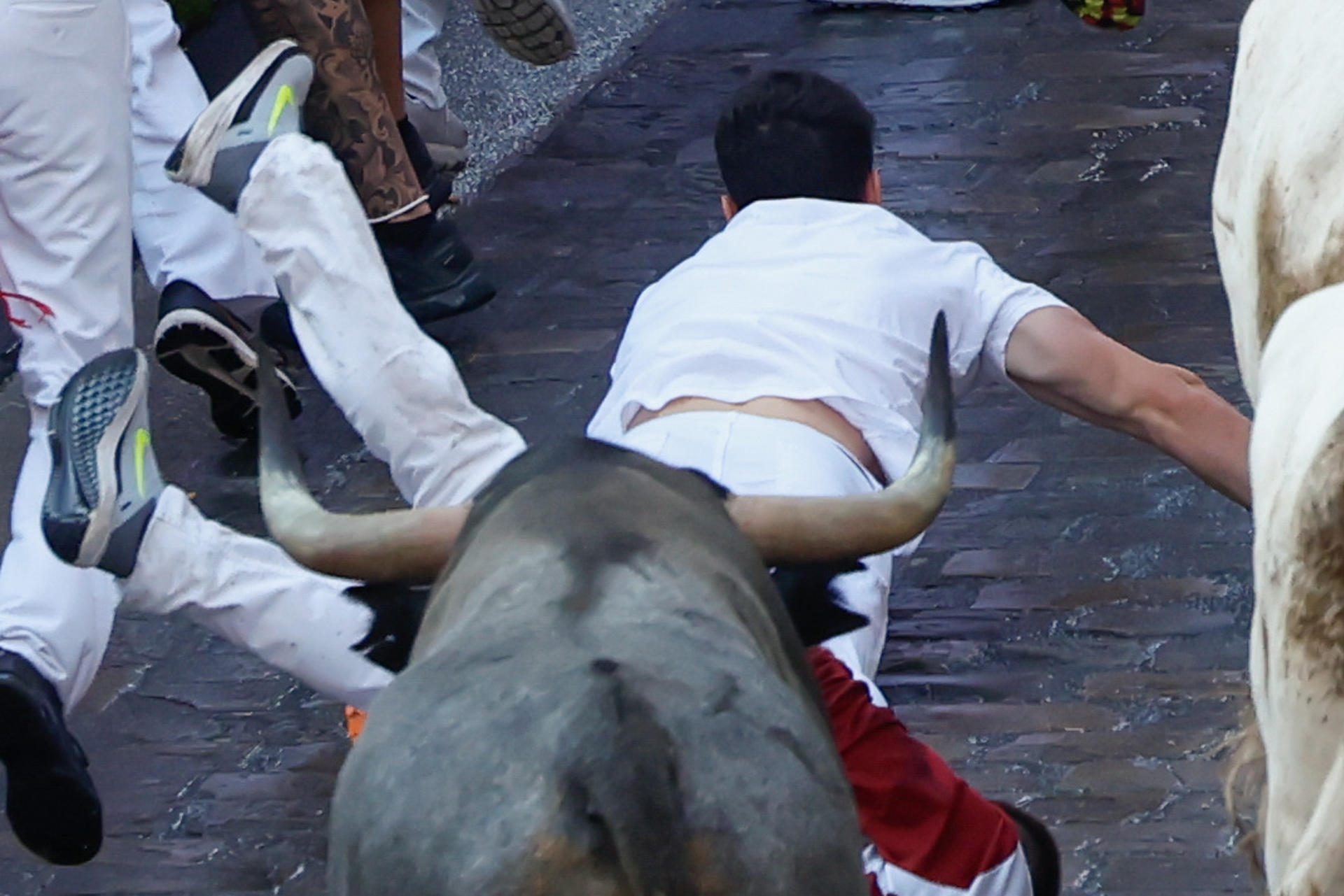 Un par de mozos caen empujados por uno de los los toros de la ganadería de José Escolar en el sexto encierro de los Sanfermines, este sábado en Pamplona. EFE/Jesús Diges