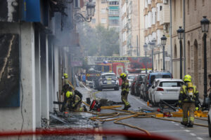 Varios bomberos trabajan en la extinción del fuego de un comercio situado en un edificio de viviendas de la Avenida del Puerto de València. EFE/Manuel Bruque