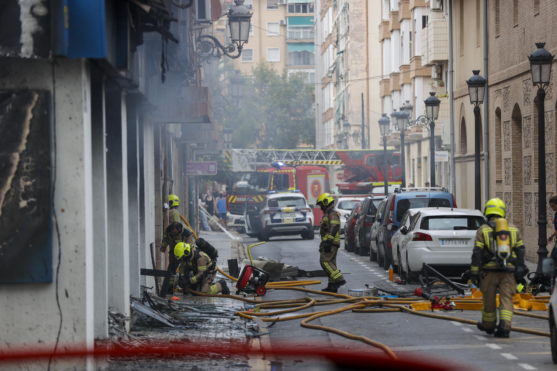 Varios bomberos trabajan en la extinción del fuego de un comercio situado en un edificio de viviendas de la Avenida del Puerto de València. EFE/Manuel Bruque