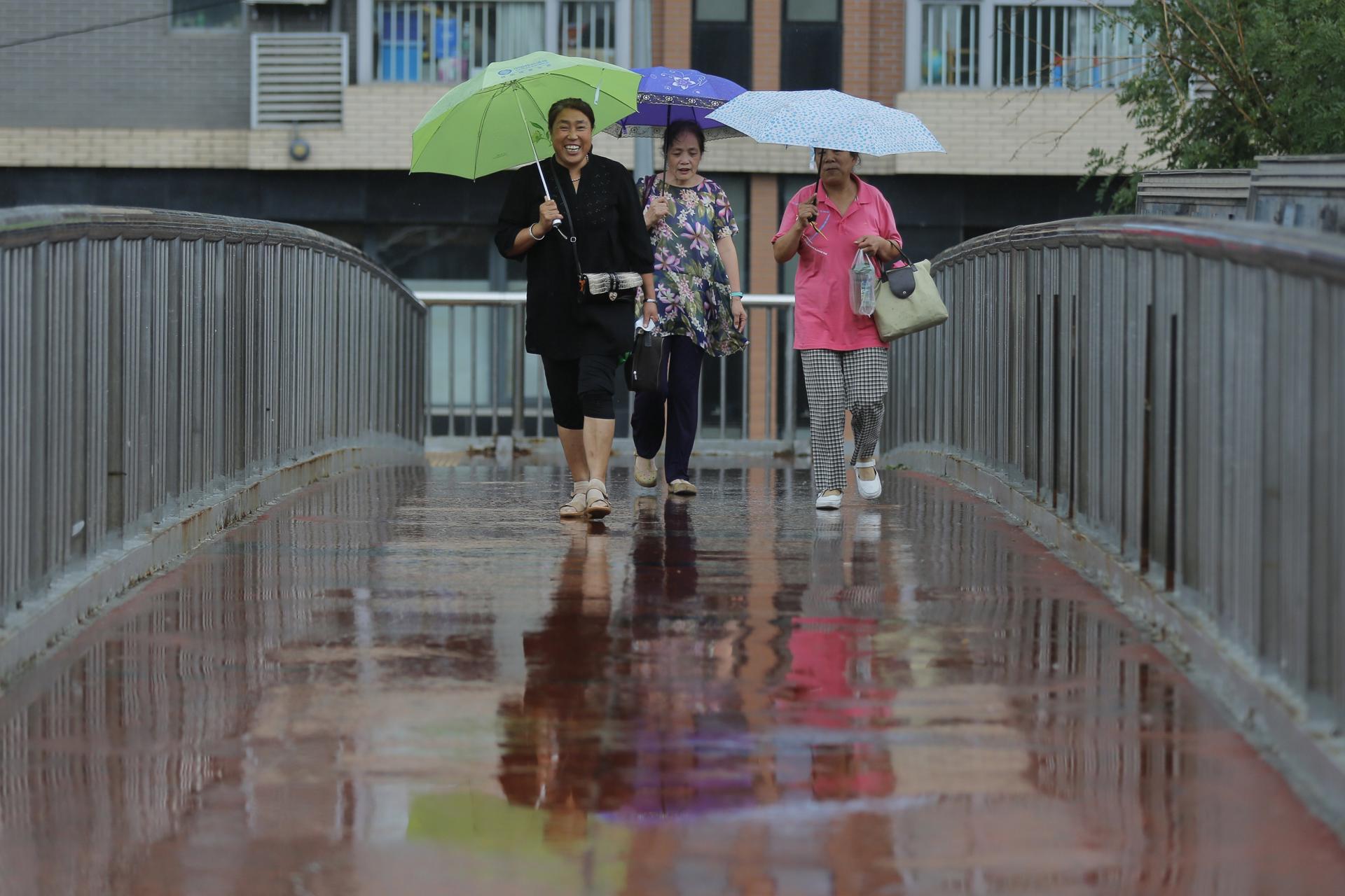 Varias mujeres caminan bajo la lluvia en Pekín (China), en una fotografía de archivo. EFE/Wu Hong