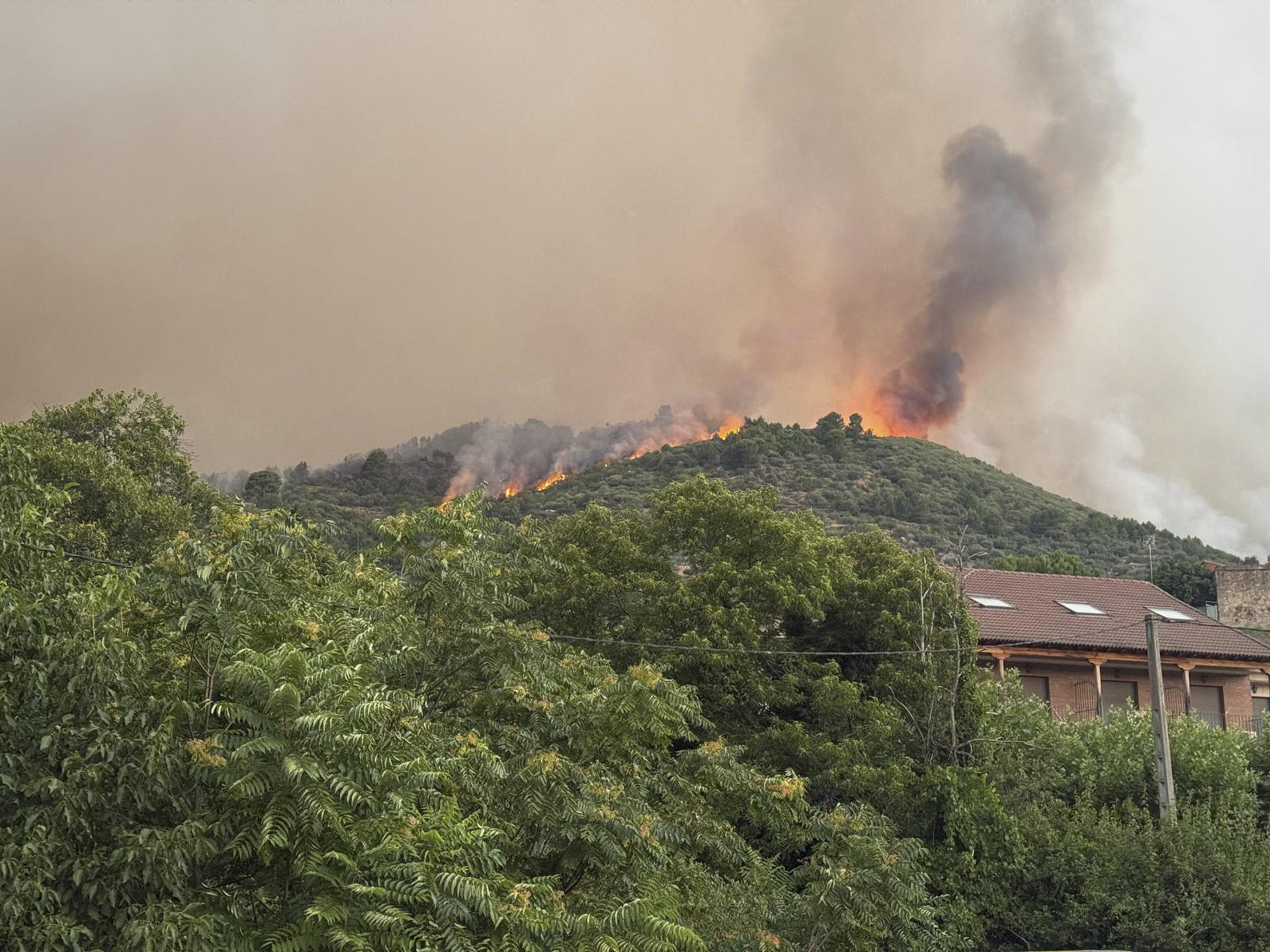 Un helicóptero de los bomberos trata de controlar el fuego declarado este martes por Mombentrán, Ávila. EFE/ Raúl Sanchidrián