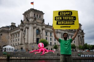 Un activista de Greenpeace sostiene una pancarta con el lema "¡Alto a la minería de aguas profundas!" frente a un pulpo inflable junto al Parlamento alemán en Berlín, Alemania, este lunes. EFE/EPA/CLEMENS BILAN