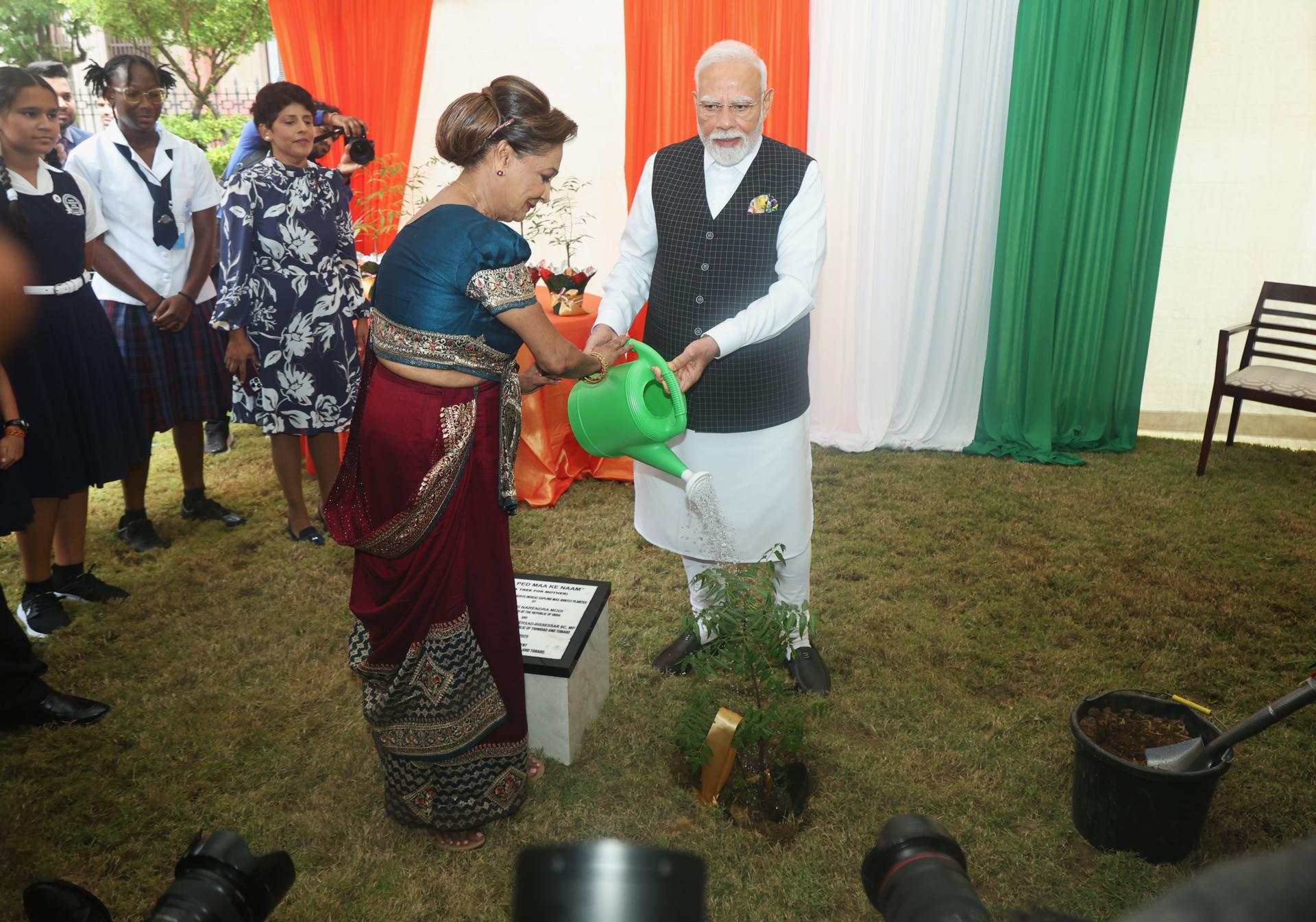 El primer ministro de la India, Narendra Modi, y su homóloga de Trinidad y Tobago, Kamla Persad-Bissessar, riegan con agua una planta de Neem este viernes en la Casa Roja de Puerto España (Trinidad y Tobago). Modi finalizó una visita de Estado de dos días a Trinidad y Tobago haciendo un llamamiento a la colaboración para "dar al sur global el lugar que le corresponde". EFE/Karla Ramoo