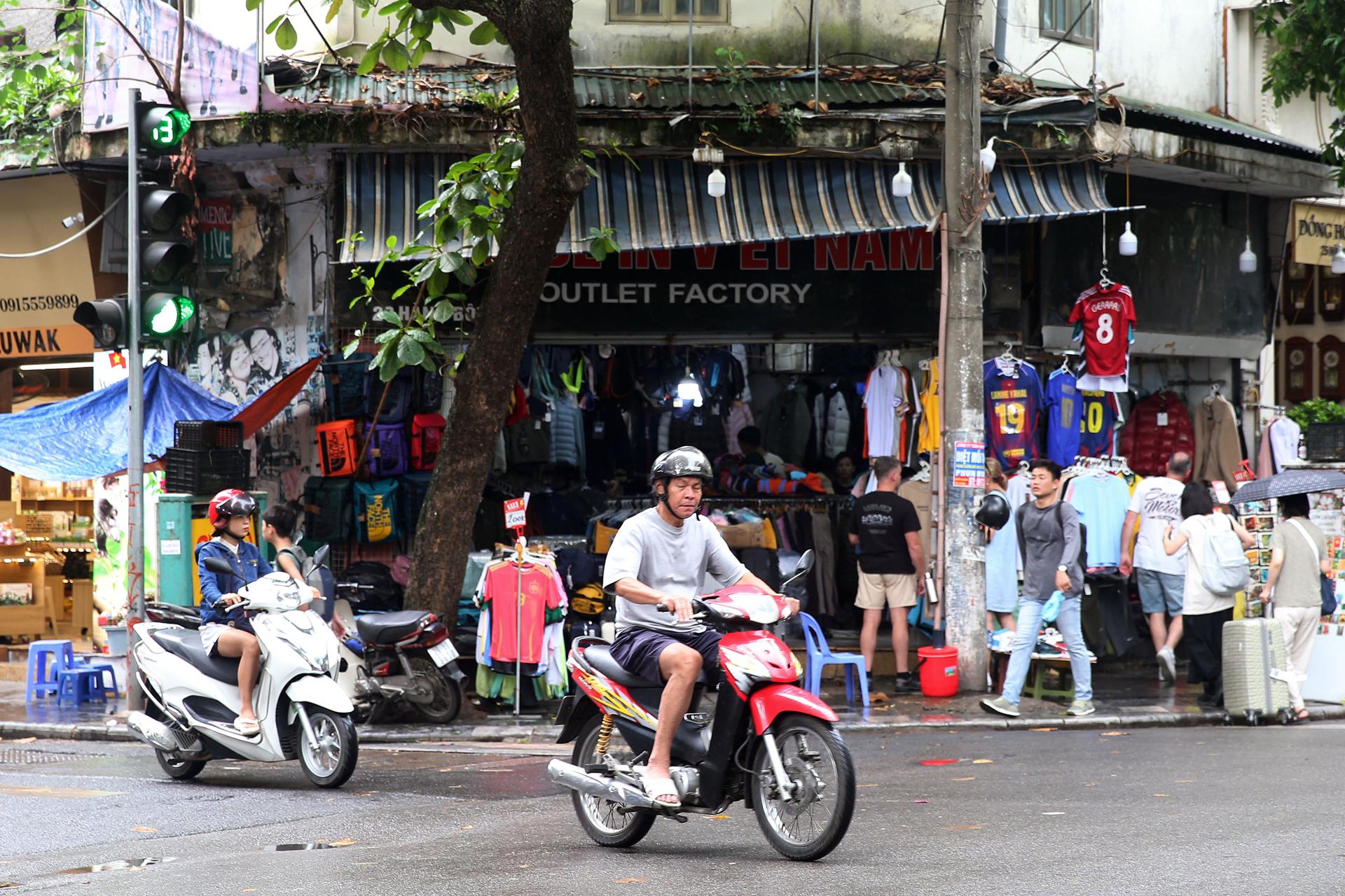 HANÓI (Vietnam), 03/07/2025.- Personas en motocicleta pasan frente a una tienda "Fábrica Outlet" en una calle de Hanói, Vietnam, el 3 de julio de 2025. EFE/EPA/LUONG THAI LINH