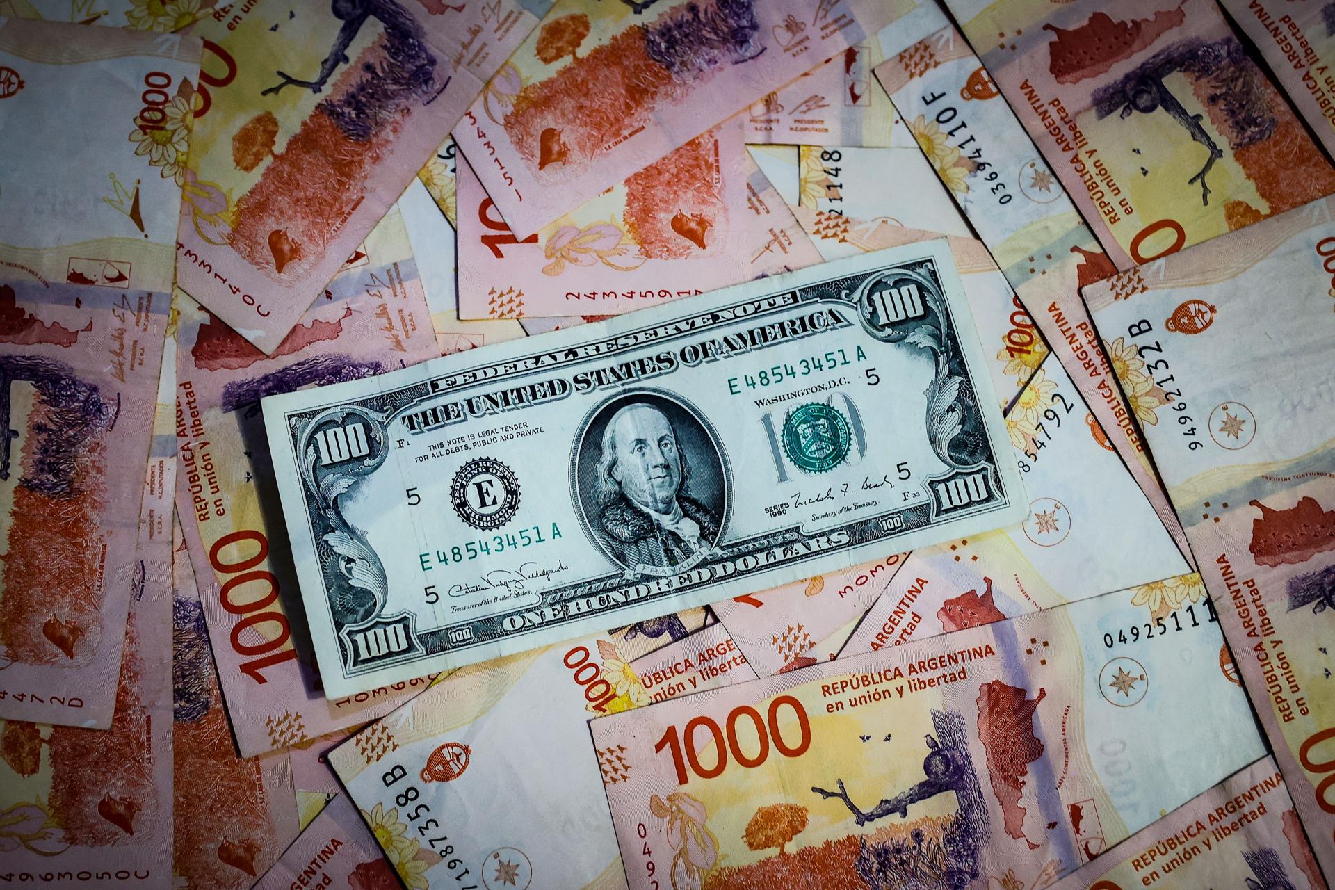 Fotografía de archivo comparativa de billetes de pesos argentinos con un billete de 100 dolares estadounidenses. EFE/ Juan Ignacio Roncoroni