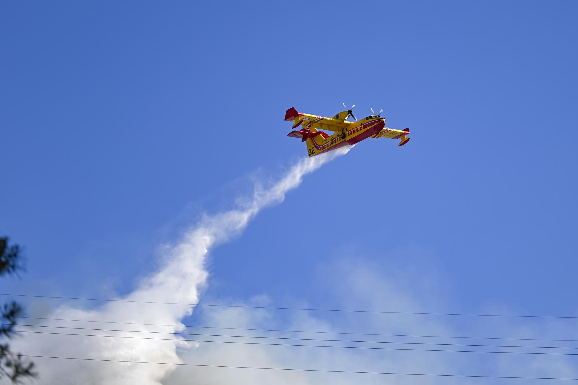 Un avión arroja agua sobre un incendio forestal que se expande rápidamente debido a los fuertes vientos cerca de la ciudad de Marsella, Francia, el 8 de julio de 2025. EFE/EPA/PHILIPPE MAGONI