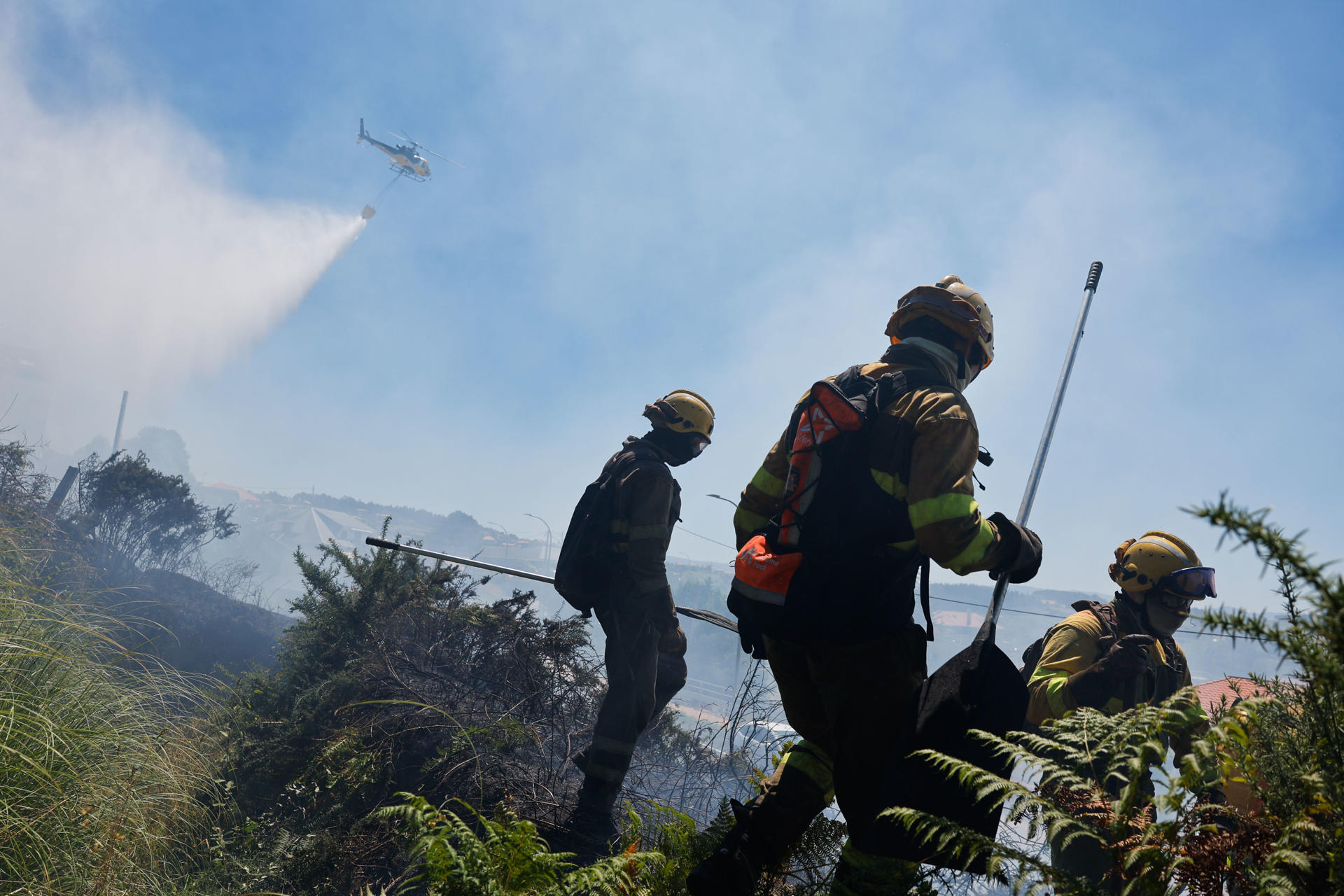 Bomberos trabajan este martes, en la extinción de un incendio en A Lanzada (Pontevedra). EFE/ Lavandeira Jr