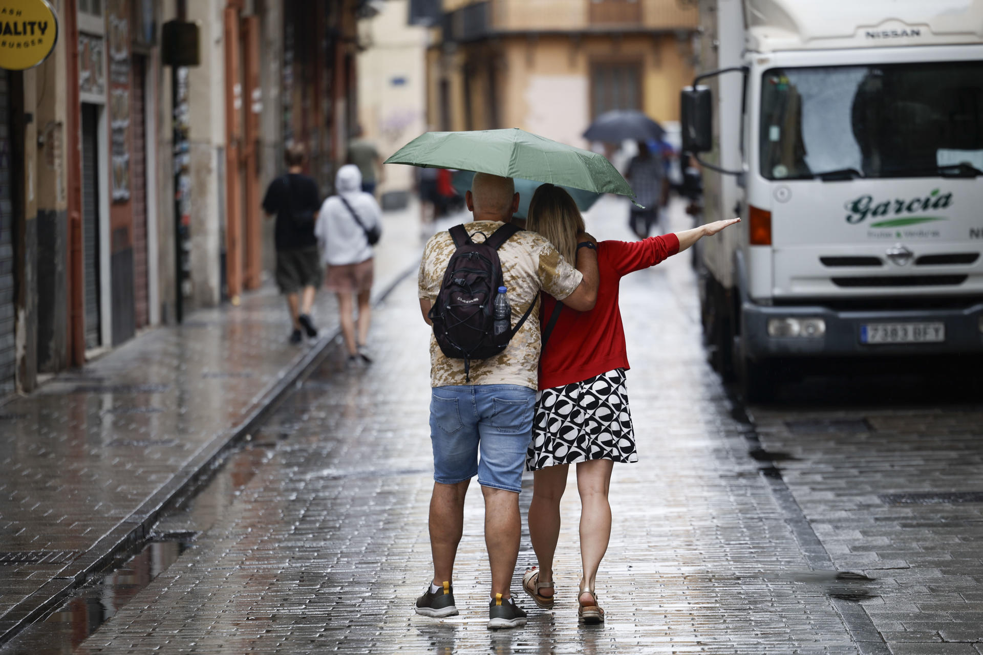 Varias personas se protegen de la lluvia este jueves en València. EFE/ BIEL ALIÑO