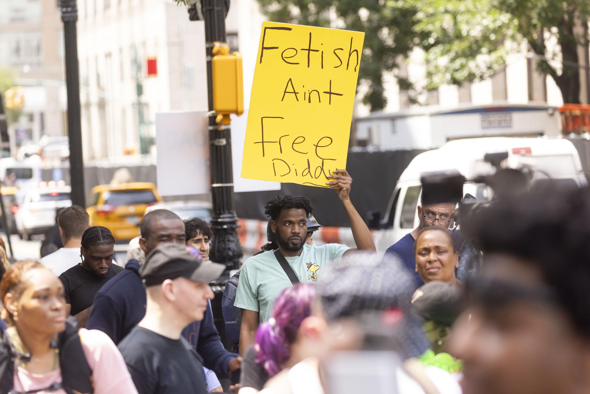 Un simpatizante de Sean Combs sostiene una pancarta frente a un tribunal federal después de que un jurado lo absolviera de los cargos de extorsión y tráfico sexual y lo declarara culpable de delitos menores de transporte en Nueva York. EFE/Justin Lane