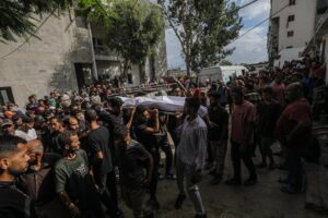 Palestinos desplazados internamente llevan el cuerpo de un joven fuera del Hospital Al Shifa después de que fuera asesinado a tiros en un punto de distribución de alimentos cerca de Zikim, en la Ciudad de Gaza. EFE/MOHAMMED SABER