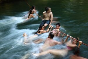 Varias personas se cuelgan de una cuerda en el arroyo Eisbach este martes, en el Jardín Inglés en Múnich (Alemania). EFE/EPA/ Anna Szilagyi