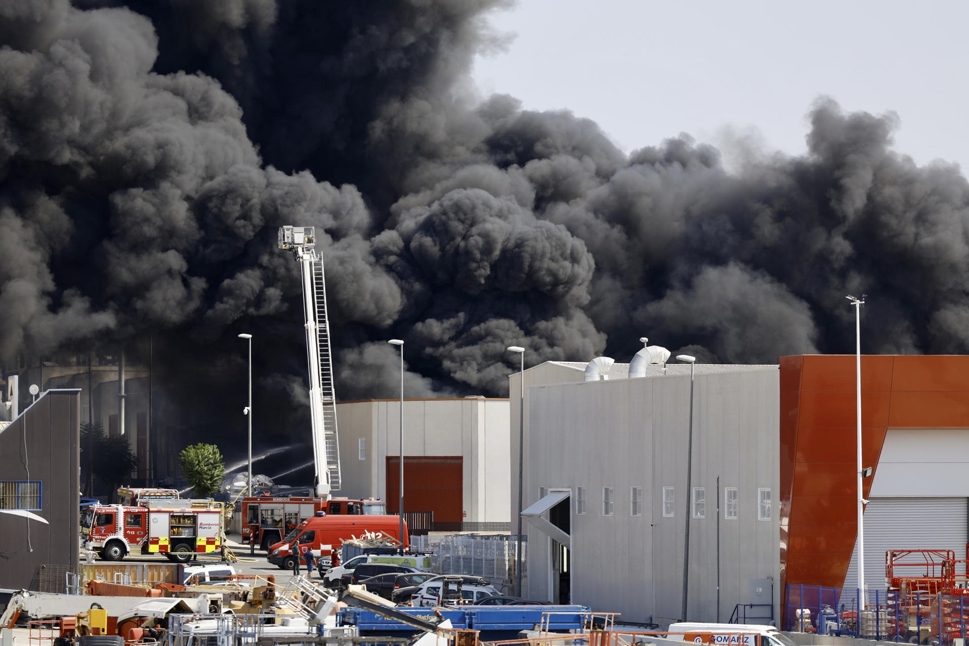 Bomberos y medios aéreos trabajan para extinguir un incendio en una nave de reciclaje de plásticos del polígono industrial de Fortuna (Murcia), que se declaró sobre las 09:00 horas y ha generado una densa nube negra con posible toxicidad. Protección Civil ha activado un aviso a la población y ha recomendado el confinamiento inmediato de viviendas cercanas, instando a cerrar puertas y ventanas y no salir al exterior. EFE/Juan Carlos Caval