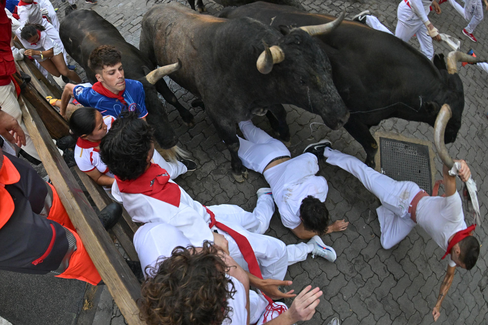 Dos mozos caen al paso de los toros de la ganadería sevillana de Miura durante el octavo y último encierro de los Sanfermines este lunes. EFE/ Daniel Fernández