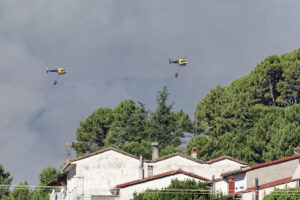 Dos helicópteros de los bomberos trata de controlar el fuego declarado este martes por Mombentrán, Ávila. Un total de 101 militares y 47 medios de la Unidad Militar de Emergencias (UME) se encuentran desplegados actualmente en el Barranco de las Cinco Villas por el incendio que se declaró en la noche del lunes en esta zona del sur de la provincia de Ávila. EFE/ Raúl Sanchidrián