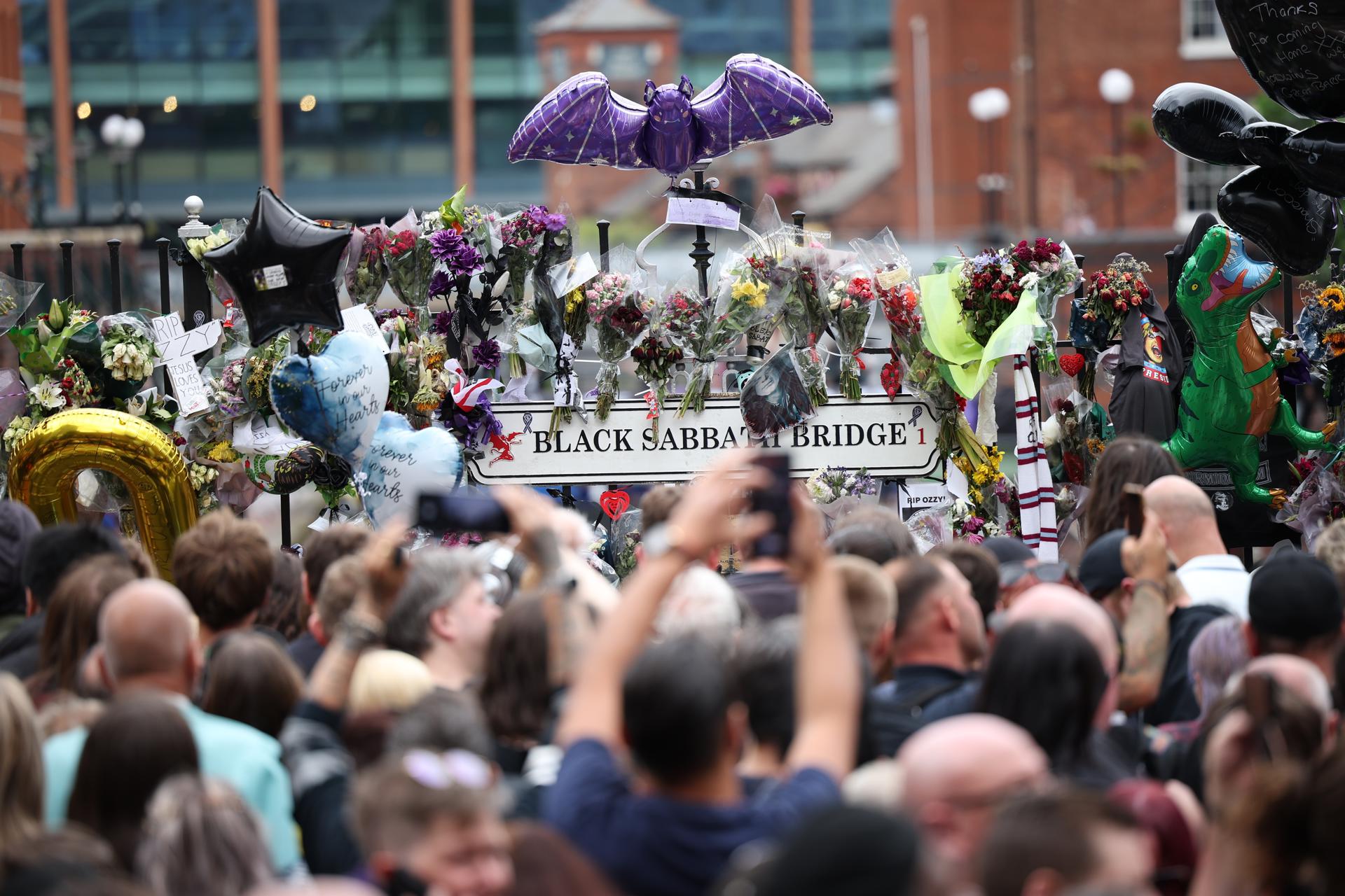 Los fanáticos toman fotos de los tributos a Ozzy Osbourne en el banco de Black Sabbath y el puente después de ver el cortejo fúnebre de Osbourne en Birmingham, Reino Unido, 30 de julio de 2025. Osbourne murió a los 76 años el 22 de julio de 2025, semanas después de realizar su último concierto con Black Sabbath. Le habían diagnosticado la enfermedad de Parkinson en 2019. (Reino Unido) EFE/EPA/ADAM VAUGHAN