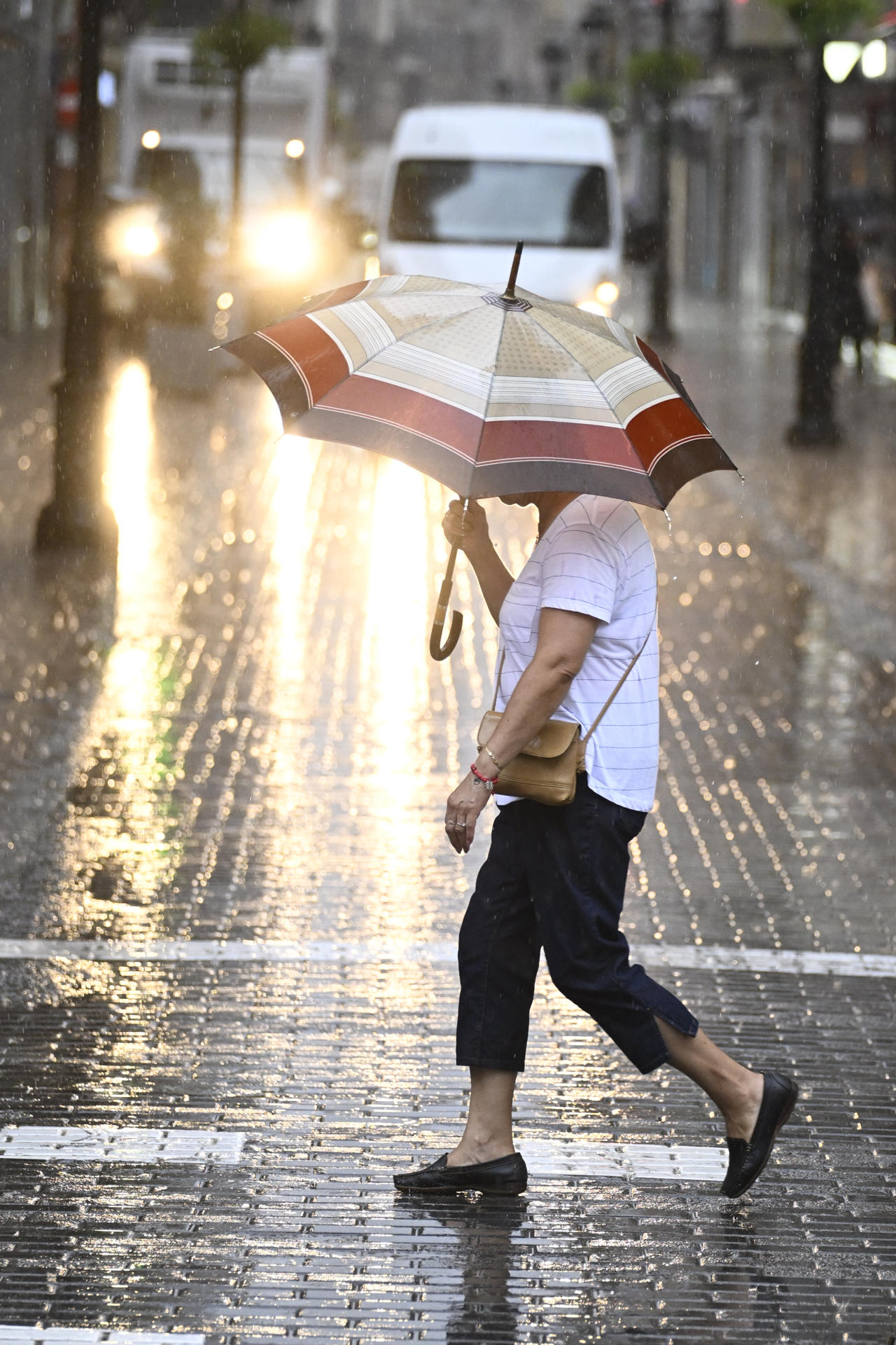 Una mujer cruza, este miércoles una calle de la ciudad de Castellón bajo una intensa lluvia. EFE/Andreu Esteban