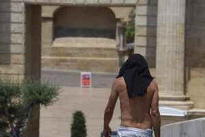 Un hombre se protege la cabeza con su camiseta, ayer martes, mientras camina por el casco histórico de Córdoba. EFE/Salas