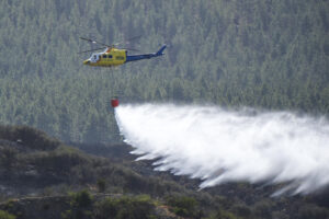 En la imagen, un helicóptero del Ministerio de Transición Ecológica descarga agua sobre la zona afectada en el término municipal de Santiago del Teide. EFE/Alberto Valdés