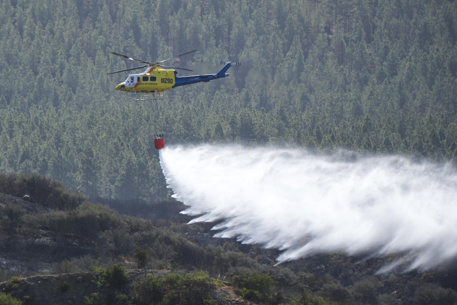 En la imagen, un helicóptero del Ministerio de Transición Ecológica descarga agua sobre la zona afectada en el término municipal de Santiago del Teide. EFE/Alberto Valdés