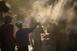 Turistas pasean por Atenas bajo el agua pulverizada por aspersores en la calle debido a las altas temperaturas en Grecia. EFE/EPA/GEORGE VITSARAS
