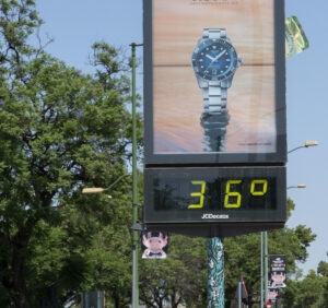 Dos personas pasan en bicicleta junto a un termómetro que marca 36 grados, este domingo en Sevilla. EFE/ David Arjona