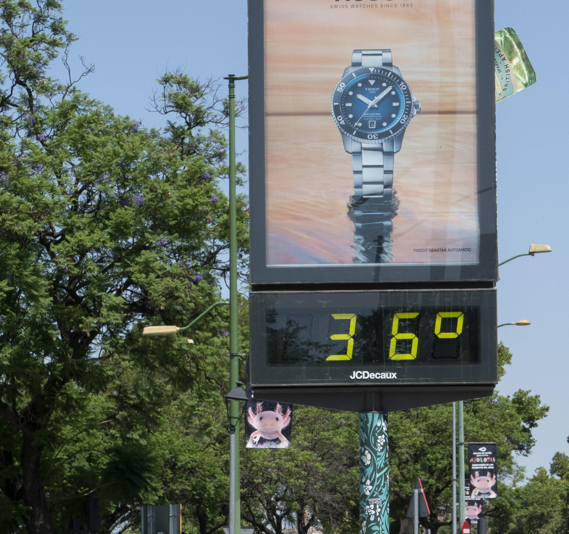 Dos personas pasan en bicicleta junto a un termómetro que marca 36 grados, este domingo en Sevilla. EFE/ David Arjona