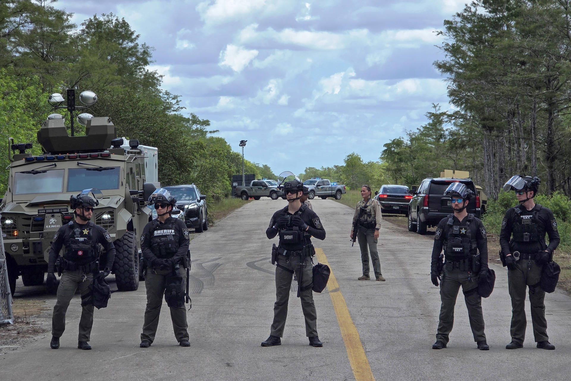 Agentes de la Oficina del Alguacil del Condado de Collier hacen guardia durante una protesta realizada contra las dependencias migratorias y los centros de detención de inmigrantes en el centro 'Alligator Alcatraz' este martes, en Ochopee (Estados Unidos). EFE/ Alberto Boal