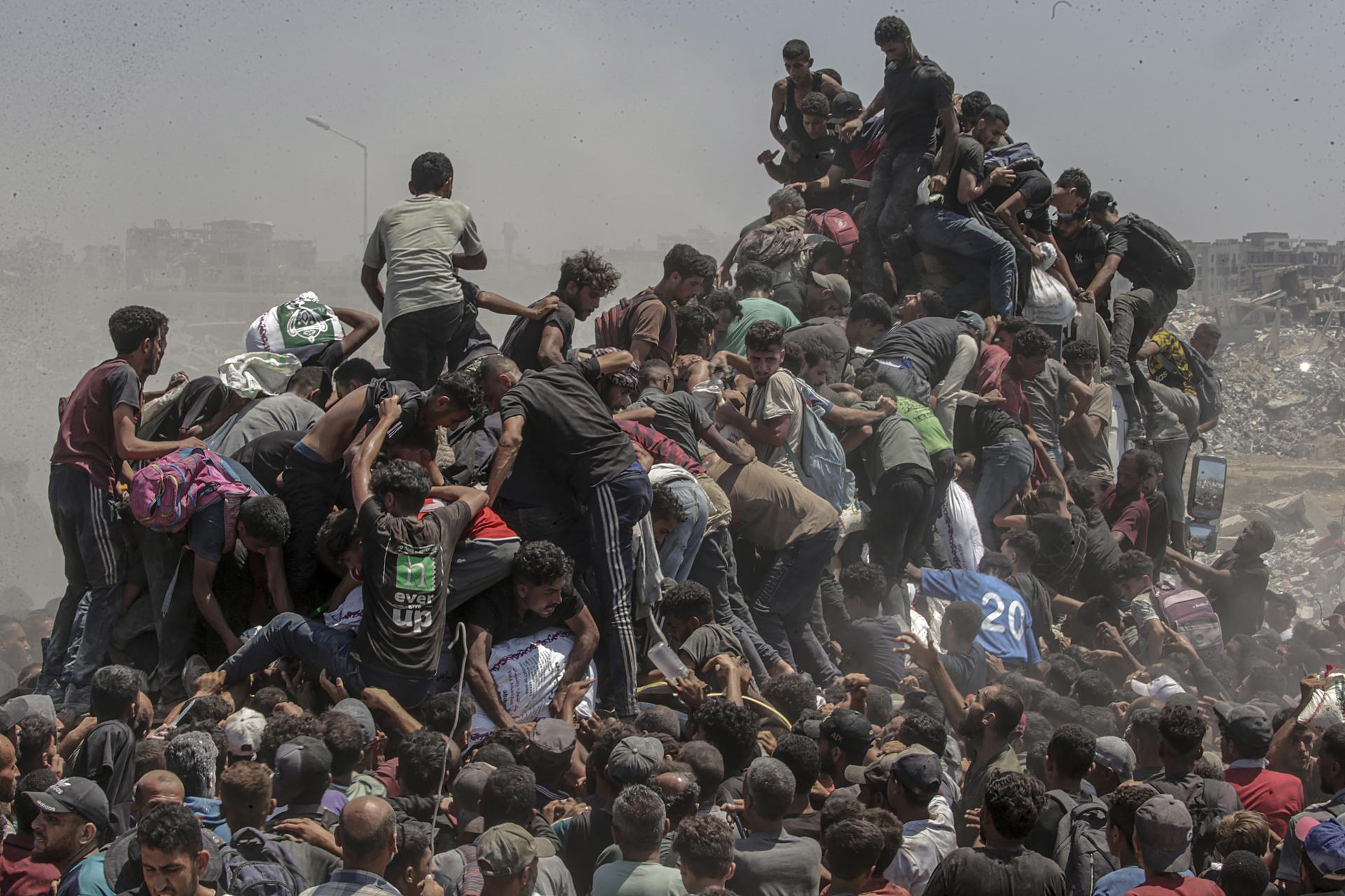 Palestinos intentan conseguir sacos de harina de un camión de ayuda cerca de un punto de distribución de alimentos en Zikim, al norte de la Franja de Gaza, este domingo. EFE/MOHAMMED SABER