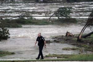 Un oficial de policía fue captado este sábado, 5 de julio, al caminar junto al terreno inundado por el desbordamiento del río Guadalupe, en Kerrville (Texas, EE.UU.). EFE/Dustin Safranek
