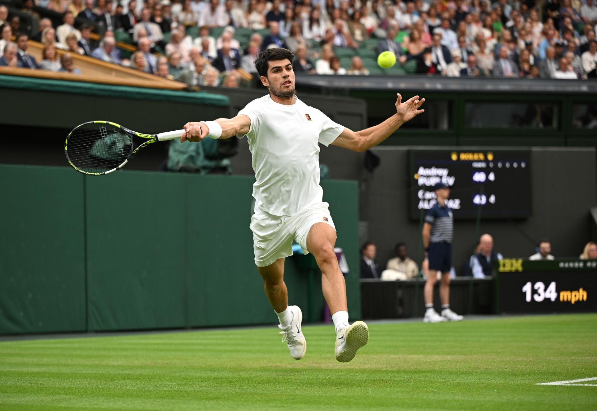 El español Carlos Alcaraz devuelve una pelota al ruso durante el partido que ambos disputan este domingo, correspondiente a los octavos de final del torneo de Wilbledon. EFE/DANIEL HAMBURY