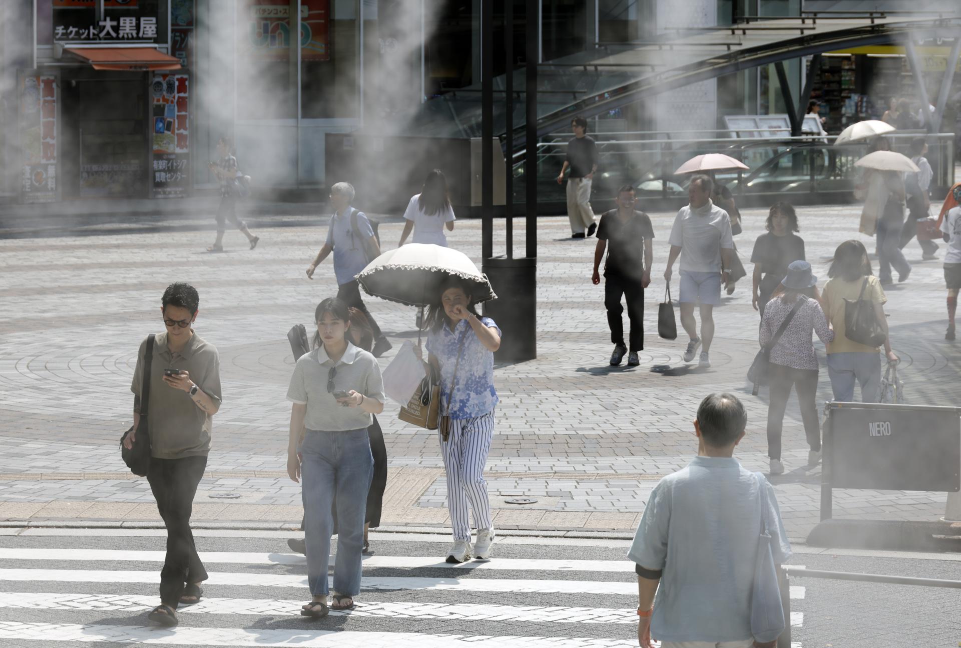 Imagen de archivo de unos jóvenes refrescándose en unos difusores de agua durante una ola de calor en Tokio (Japón). EFE/EPA/FRANCK ROBICHON